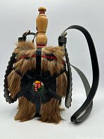 Front view showing fur covering, leather overlay, crest, strap and stopper