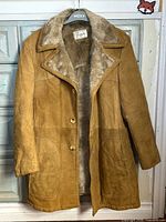 Front view of tan suede shearling coat showing buttons, pockets, collar