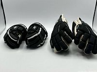 Two pairs of black youth hockey gloves displayed side by side