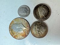 Obverse view of four coins: Kennedy half, Roosevelt dime, two Canadian quarters