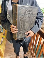 Front cover and spine of large embossed Holy Bible held for scale