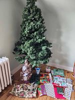 Overall shot showing artificial tree, tabletop tree, storage bag, lights, tree skirt, gift bags and decorations