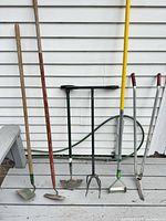 Group shot of five long-handled garden tools standing upright