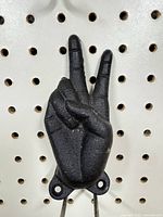 Front view of cast iron peace sign hand hook showing design and mounting holes