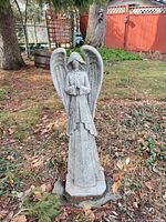 Full view of cast stone angel statue standing in garden