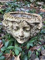 front view of planter showing face motif and moss patina