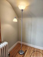 Full view of IKEA torchiere floor lamp with reading arm illuminated