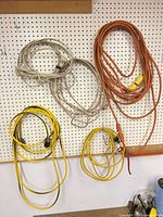 Overview of five coiled extension cords on pegboard