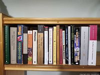 Front view of all 20 book spines on a wooden shelf