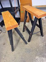 Pair of folding sawhorses angled view showing wood tops and metal legs