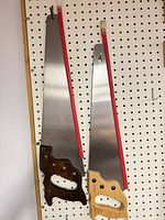 Both hand saws hanging on pegboard