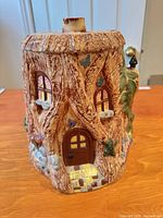 Front view of tree-trunk fairy cottage cookie jar showing door, windows, hand-painted details