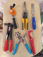 Six assorted hand tools laid out on a table