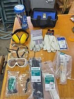 All items laid out on workbench showing tool bag, bungees, hearing protection, gloves, eye protection, cable tie packages and accessories