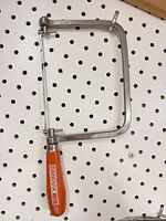 Coping saw hanging on pegboard showing full frame, handle and blade
