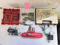 Full lot overview with SKIL screwdriver, charger, drill bit set, driver bit cases, loose bits