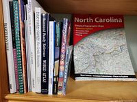 Shelf view showing assorted travel books including Bartlesville, Arizona, Blue Ridge Range, Hammond World Atlas and others