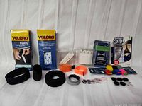 Full lot showing boxed Velcro tapes, packaged fasteners, Smart Grip pack, loose straps, coloured pads and coins