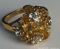 Oblique view of gold-tone floral ring showing textured petals and rhinestones