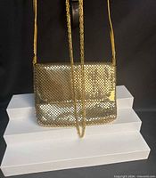 Front view of gold-tone metal mesh evening bag with chain necklace draped