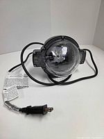 Front view showing clear dome lens, attached power cord, caution tag