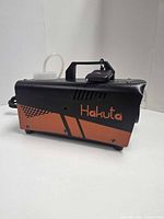 Left side profile of Hakuta fog machine showing brand logo and copper accent