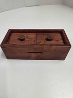 Closed wooden puzzle box top view showing two round pegs on lid