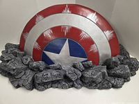 Front view of Captain America shield embedded in rock base