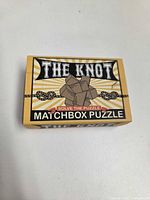 Front of closed yellow matchbox displaying puzzle branding