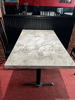Rectangular gray laminate table top with marble pattern on black pedestal base