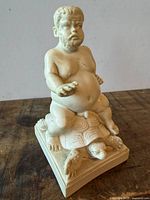 Front view of cream-toned Bacchus figurine on turtle, square base visible