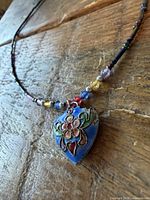 Close view pendant and nearby beads on wood surface