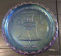 Top view of iridescent Liberty Bell carnival glass plate showing design and colour