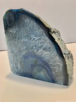 Front view of polished blue agate slice showing banding and raw edge