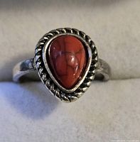 Front view of silver-tone ring with pear-shaped red cabochon stone and rope bezel