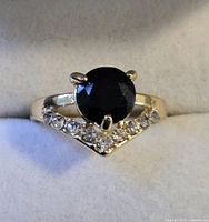 Ring front showing black center stone and clear accent stones