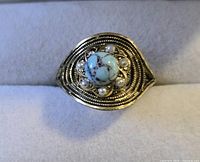 Front view showing gold-tone filigree ring with turquoise stone and pearls