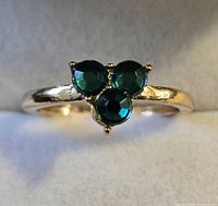 Gold-tone ring with three green stones on display