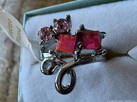 Ring on box showing front design with square and round pink stones