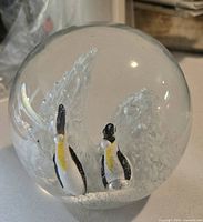 Front view of glass paperweight showing two penguins and ice detail
