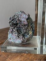 Front view of iridescent hematite cluster on acrylic base