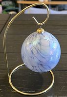 Light blue and white swirled glass ornament on gold-tone stand