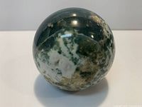 Front view of polished moss agate sphere showing color patterns