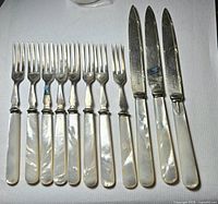 Full view of 8 forks and 3 knives showing mother-of-pearl handles and silver-plated ends