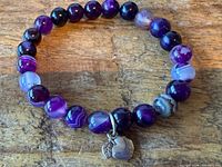 Full view of purple agate beaded bracelet showing apple charm