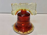 Front view showing red glass Liberty Bell form, amber crown, 1776-1976 embossing