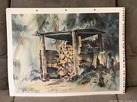Front view of one print showing rural woodpile scene, paper edges, punch holes, and color strip visible