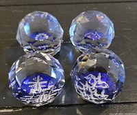 Group of four faceted crystal paperweights showing varied etched motifs