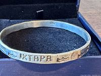 Overall view of sterling bangle inside presentation box showing exterior IXTAPA, wave and sun motifs