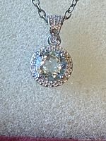 Close-up of pendant showing blue topaz, halo, bail detail